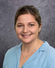 Michelle Delco in a gray background with a light blue blouse.