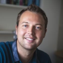 Robin Dando in office wearing a turquoise cardigan and striped blue dress shirt.