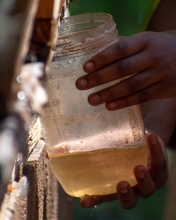Hands of a child filling up a jar with dirty water