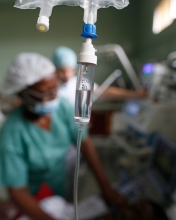 An intravenous drip on the foreground with blurry medics in the background