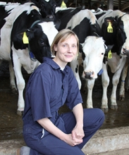 Sabine Mann in a navy-blue jumpsuit in front of at least three cows.