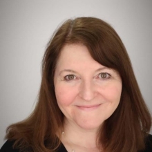Kimberly O'Brien smiling while standing in front of an off-white background.