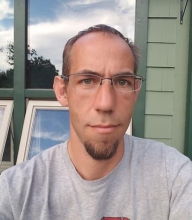 Brian Lazzaro wearing a grey shirt outside.