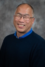 Dr. Dave Lin smiling for the camera in front of a gray background.