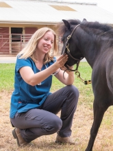 A women with blonde hair petting a horse