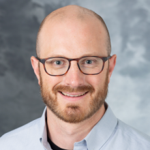A professional portrait image of Dr. Adam Bailey.