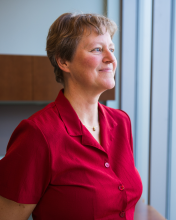 A woman wearing a red shirt looking into the distance. 