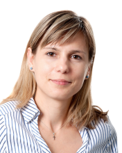 A woman wearing a striped shirt against a white background. 