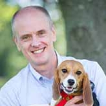 Alexander Travis smiling at the camera with his pet beagle.