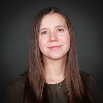 Headshot of a woman on a gray background. 