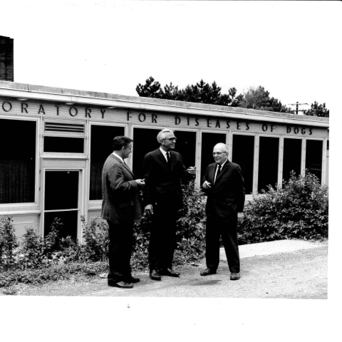 Black and White photo of exterior of Baker Institute with three men standing in front