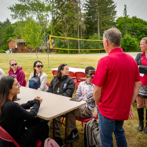 faculty member in red shirt speaking to group of students