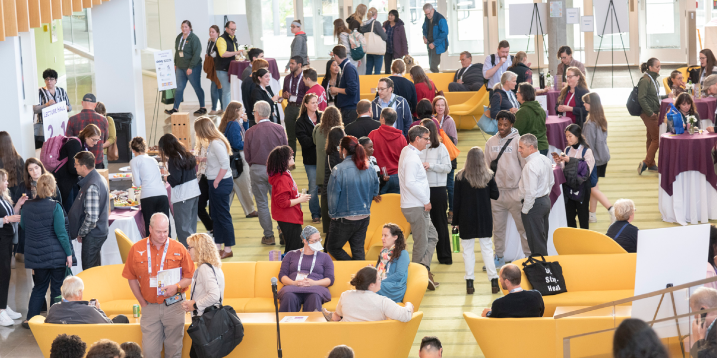 A crowd of conference attendees mingling in the CVM atrium