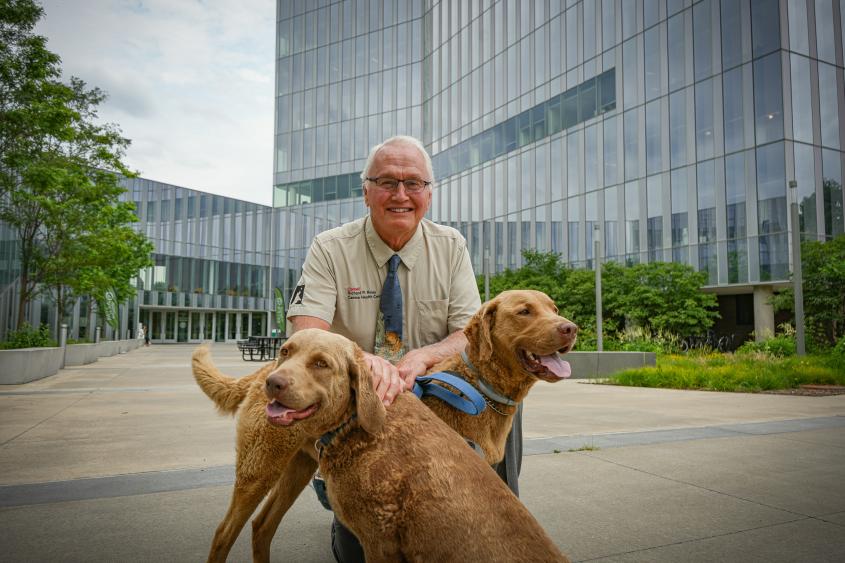 Dr. Rory Todhunter appears with his two dogs in front of the Cornell University College of Veterinary Medicine