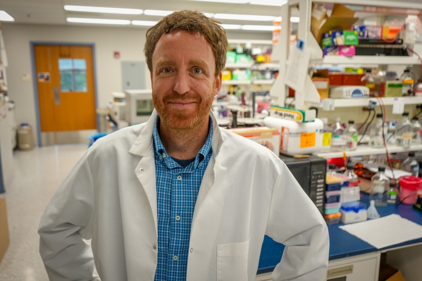Photo of Charles Danko wearing a lab coat in his lab at the Baker Institute. 