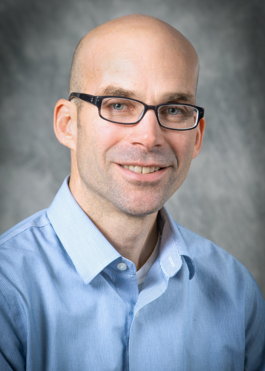 Brian Rudd wearing a blue-collared shirt.