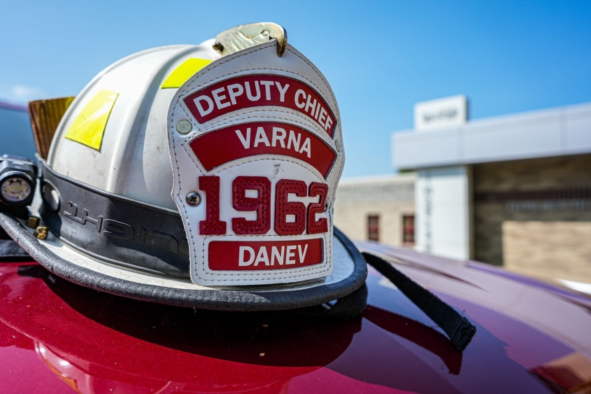 A Varna firefighter helmet sits on the hood of a red vehicle. 