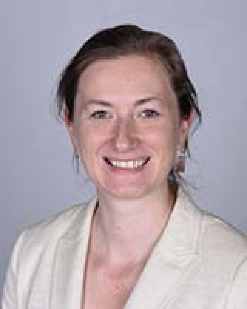 Casey Cazer wearing a white blazer in front of a grey background.