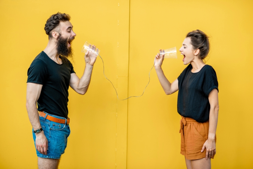 People talking into cups connected by a string
