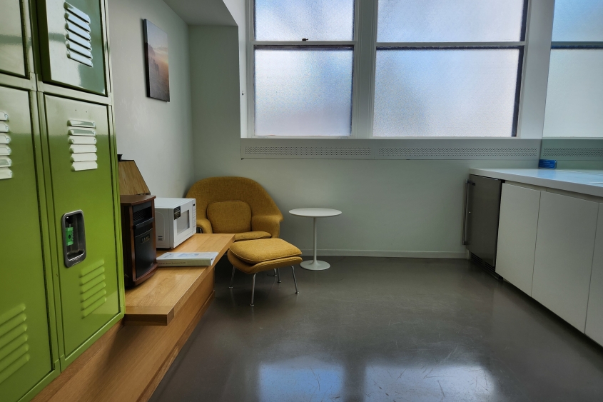 A comfortable room with an armchair, a sink and storage