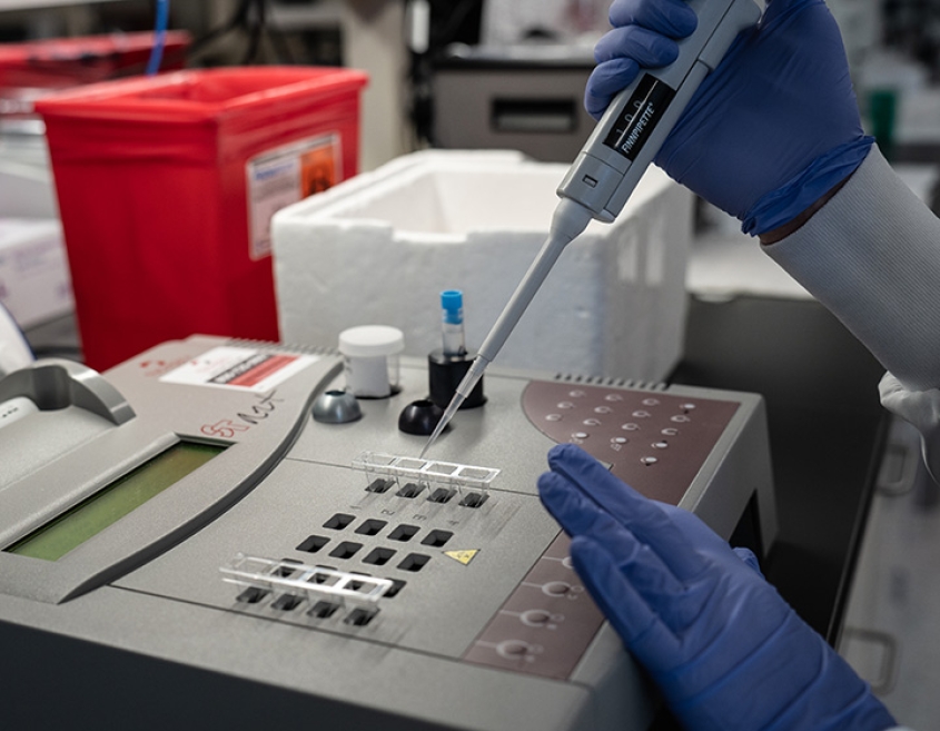 A scientist pipetting a liquid in an instrument