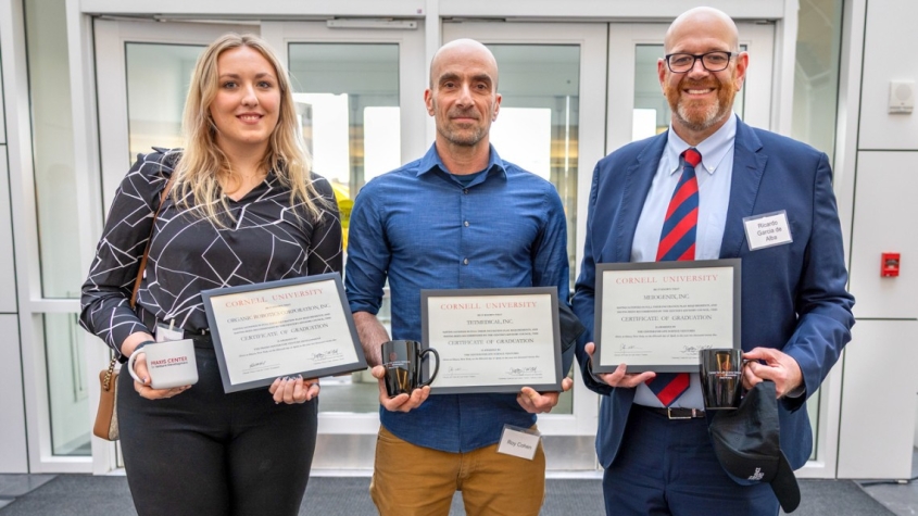 three faculty members holding plaques from the incubator graduation ceremony