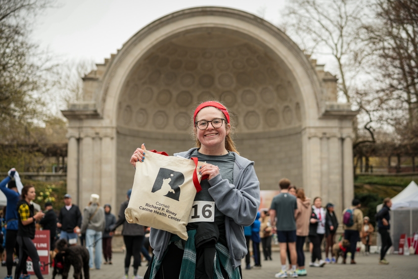 A woman stands with a Riney gift bag in front of a stage. 