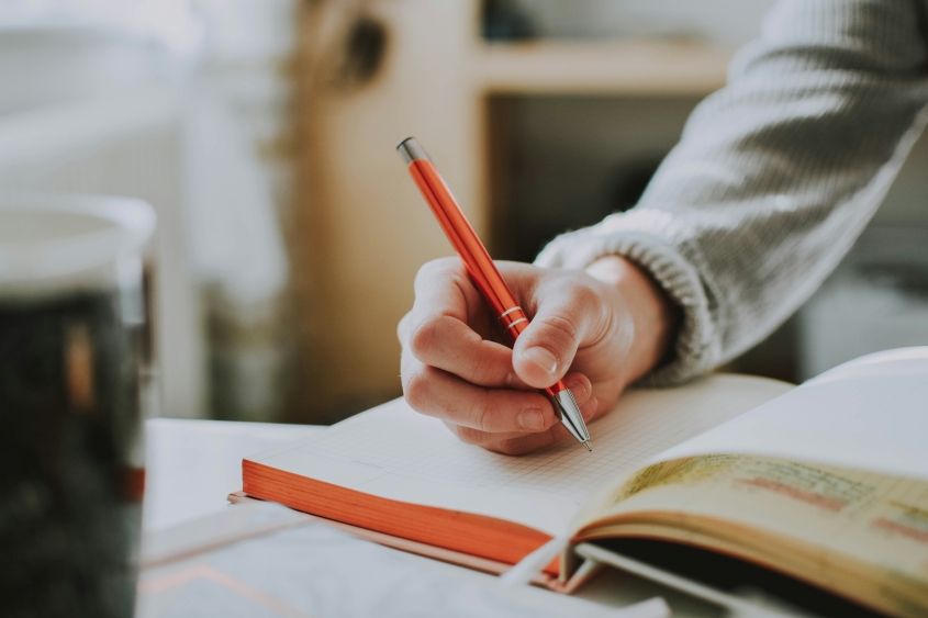 A hand writing in an open notebook