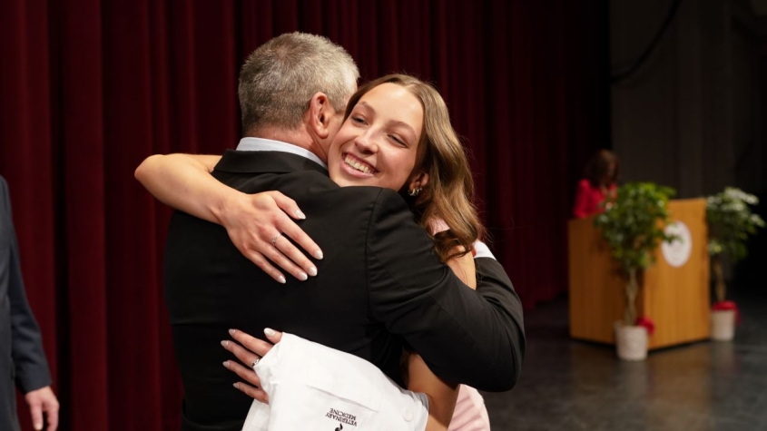 A student embraces their mentor at the White Coat Ceremony