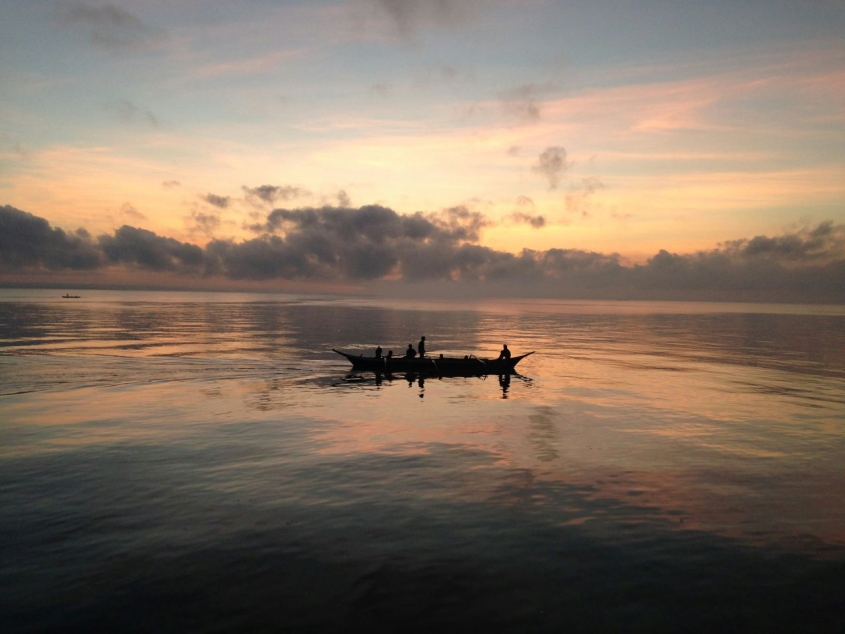 people in a fishing boat at sunset