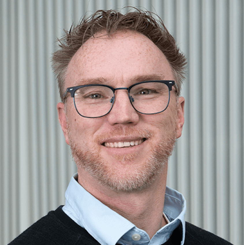 Jonathan Butcher in a light, blue-collared shirt and a black cardigan.