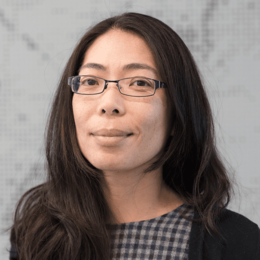 Nozomi Nishimura standing in front of a white marble background.