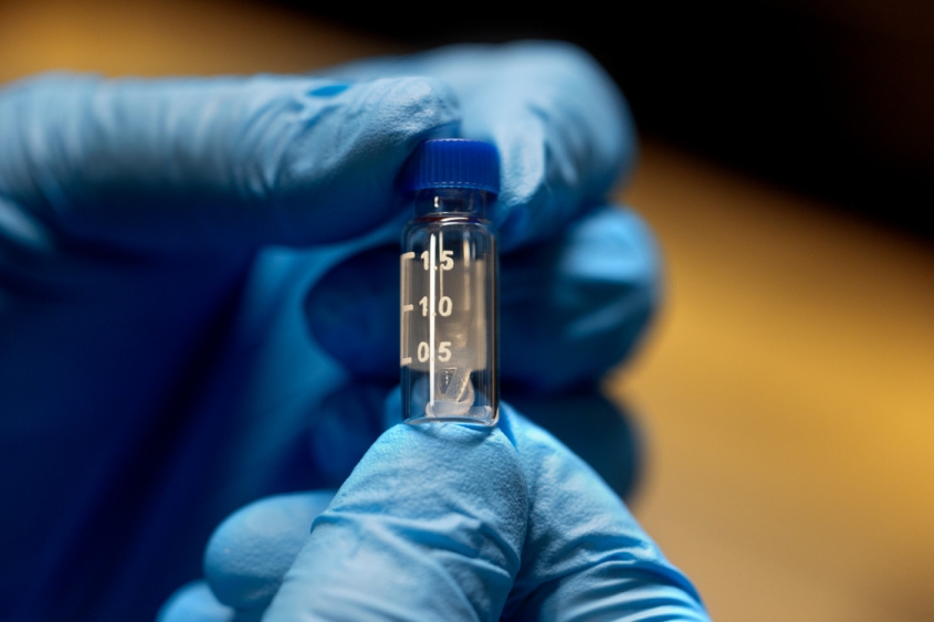 Gloved hand holding a vial
