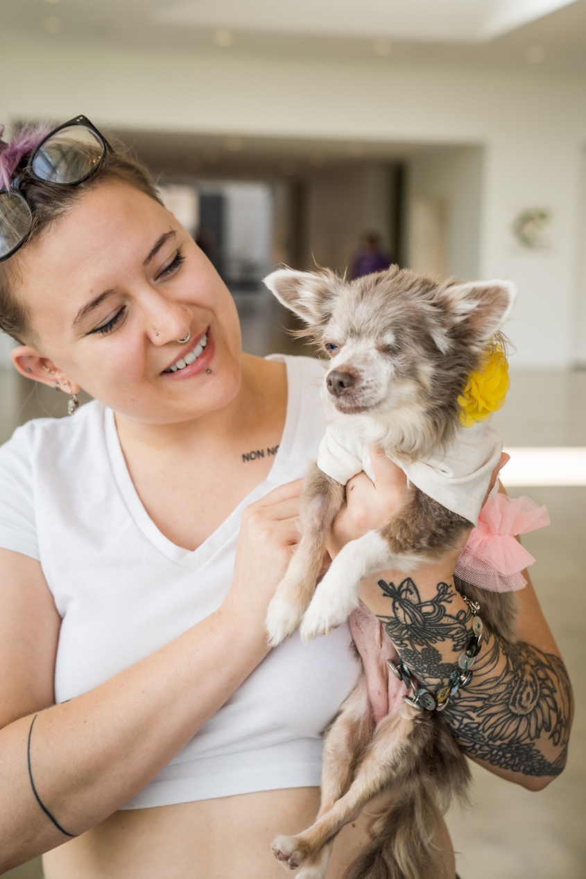 A young woman smiling and holding a tiny dog