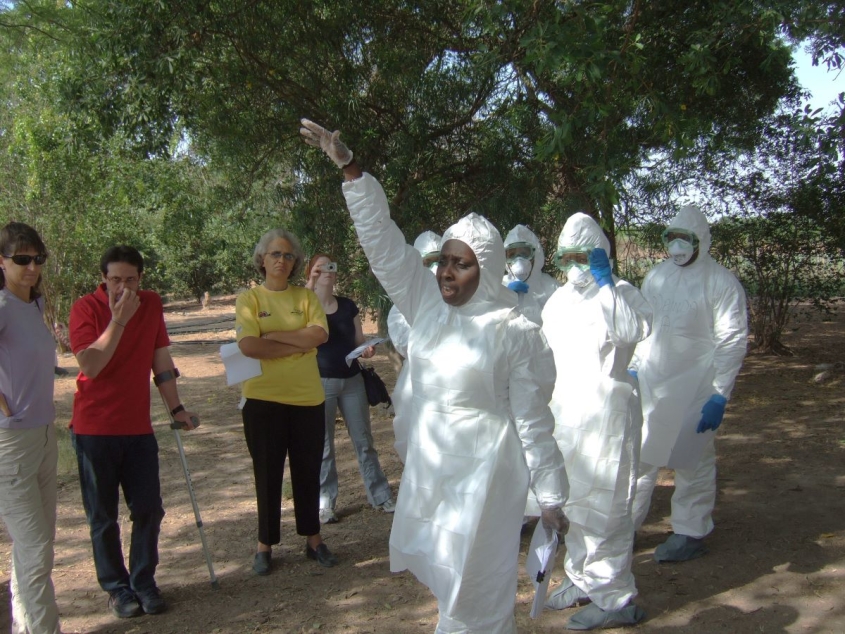 Jagne in white PPE teaching a group of people outside