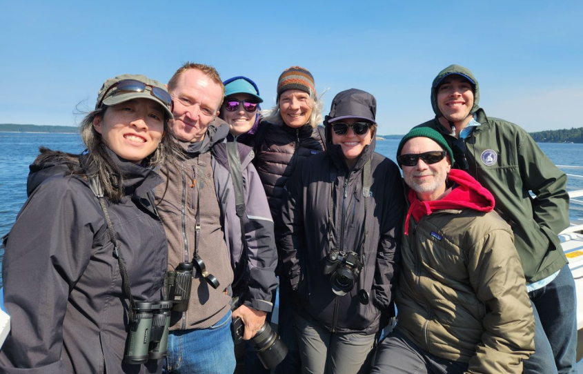 group of people in rain jackets smiling on a boat