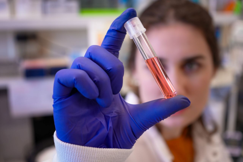 scientist holding a vial of pink liquid