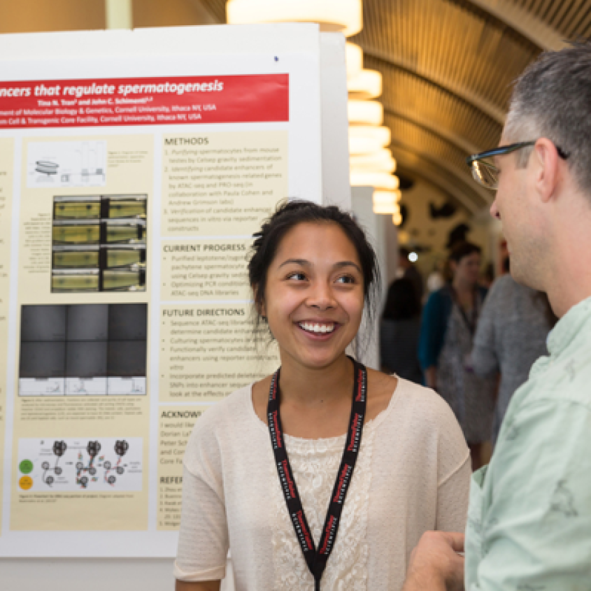A smiling student in front of her poster