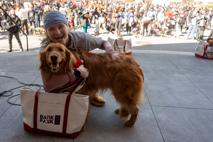 A woman smiles with a Golden Retriever. 