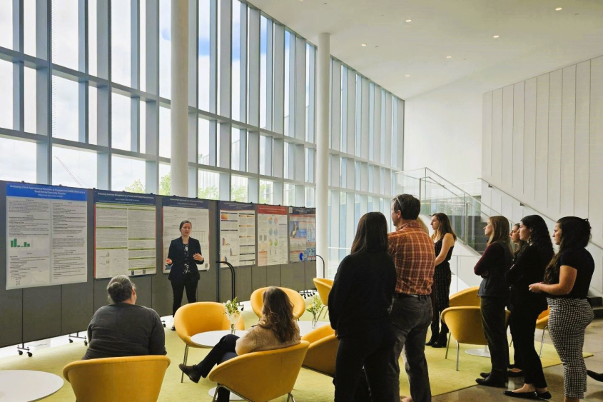 A person presenting information from a poster to a group