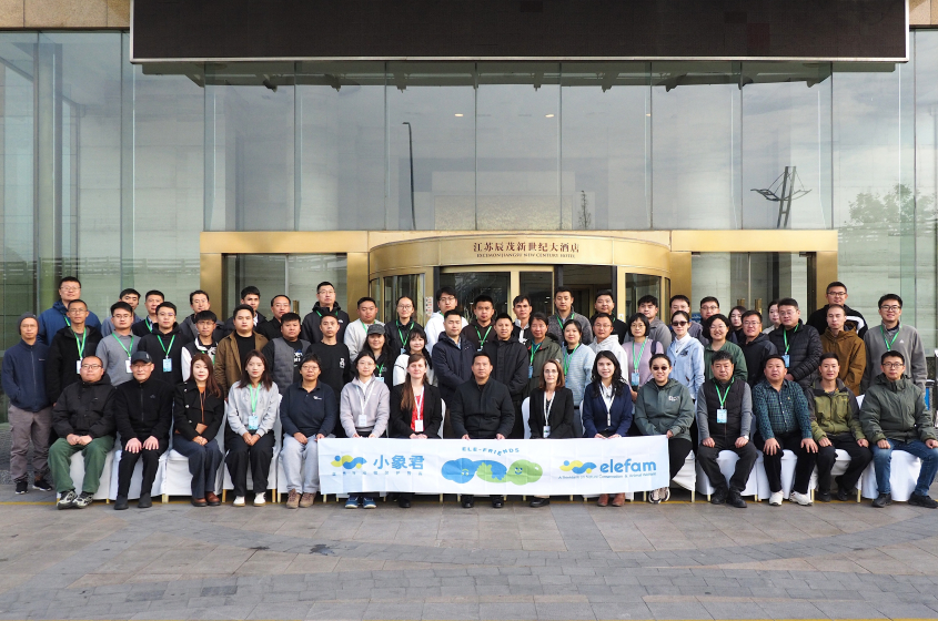 A group of approximately 50 conference attendees pose together outside the conference hotel