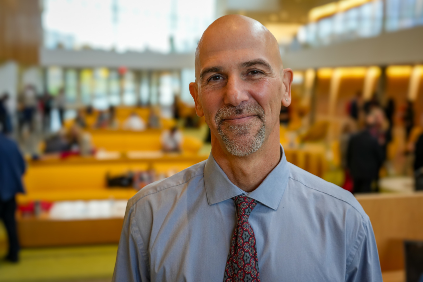 Picture of man in dress shirt and tie standing in front  of CVM atrium.