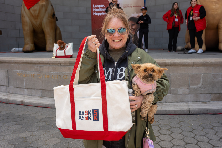 A woman with glasses on poses with her dog. 