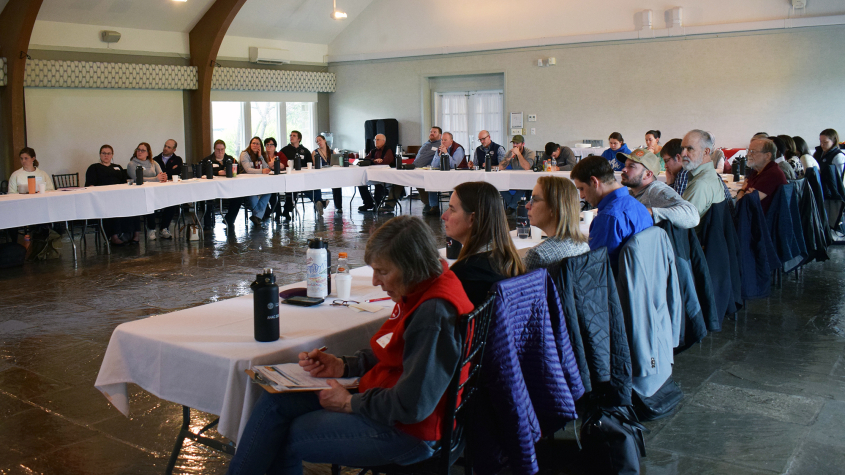 Council members taking notes along a U-shaped table