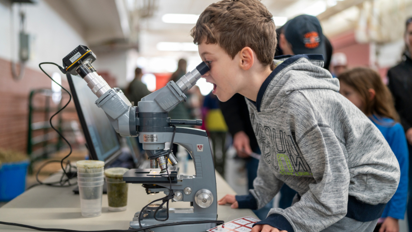  a child looking into a microscope with a wonder look on his face