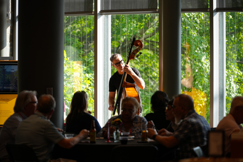 A man plays a standup bass in front of a crowd. 