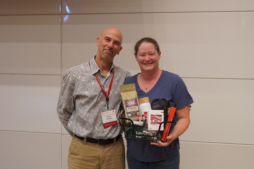 A man and woman stand together holding a prize basket with FHC items. 