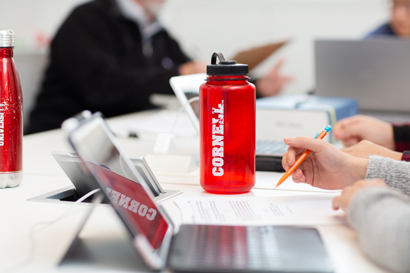 Student working at laptop with red Cornell water bottle