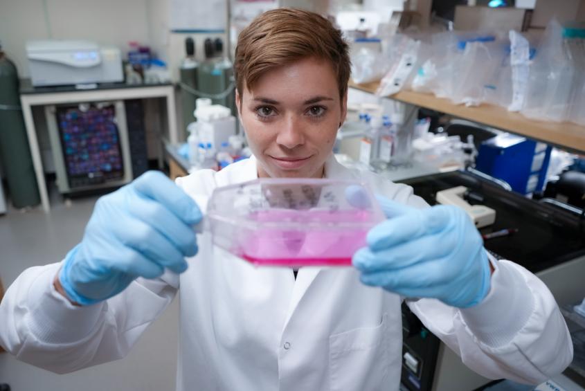Kerkenpass appears looking at a vial of pink liquid in a lab setting 