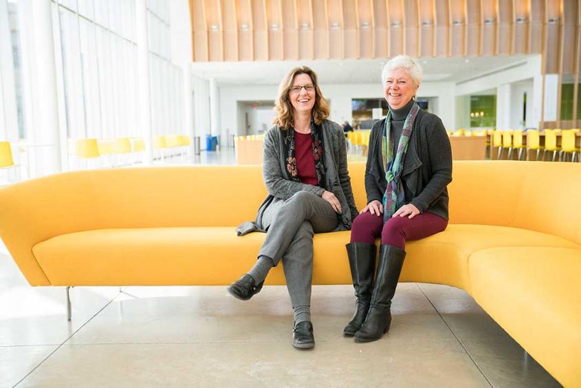 Jodi Korich and Julie Powell sitting on a couch in the Schurman atrium